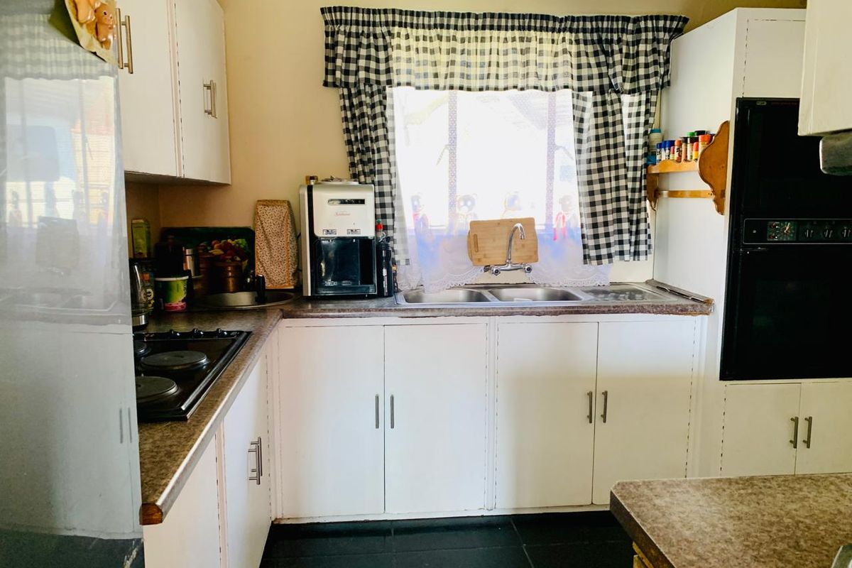A functional kitchen featuring white built-in cabinetry, laminate countertops, a double basin sink, and integrated oven and hob appliances.