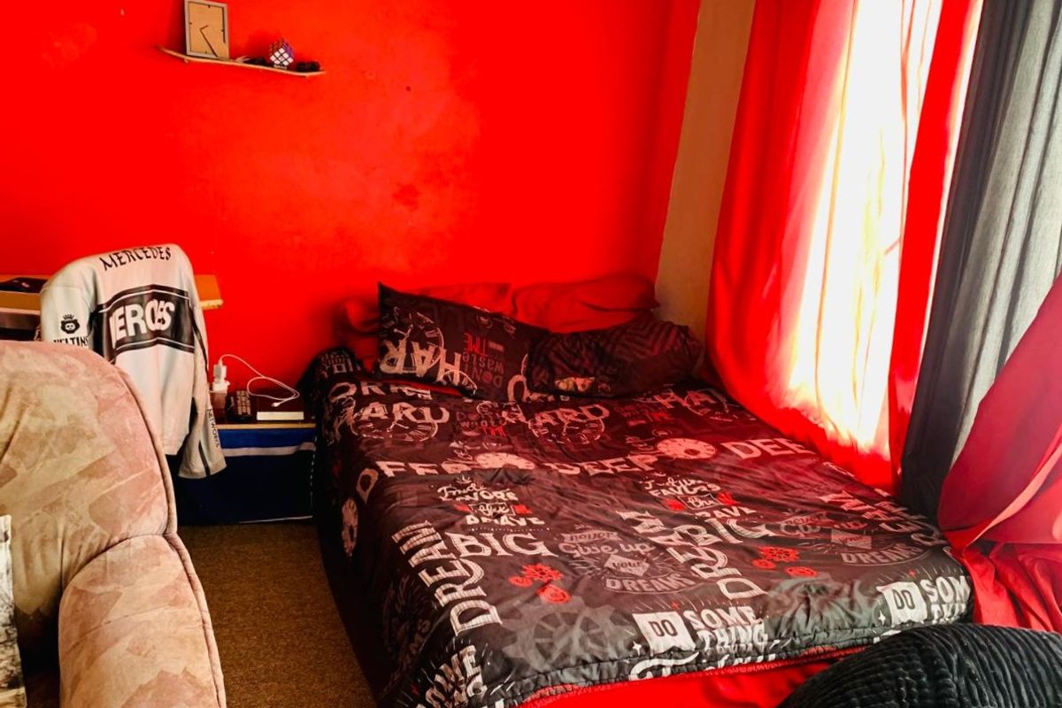 A bedroom featuring a window with red curtains and a bold red accent wall.