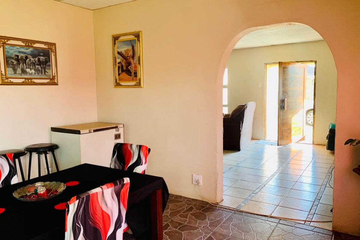 A living area featuring tiled flooring, an arched entryway leading to the front door, and a drop ceiling.