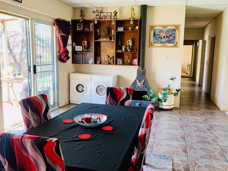 Dining area featuring tiled flooring, a built-in shelving unit, and a fireplace, with direct access to the outdoor patio through sliding glass doors.