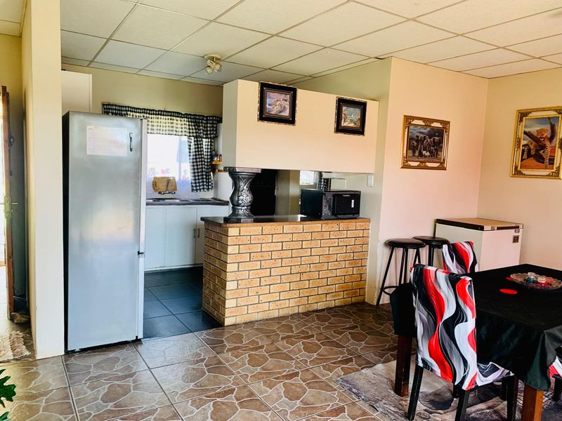 Open plan living and kitchen area featuring a brick breakfast bar, tiled flooring, and a drop ceiling, offering a functional layout for daily living.