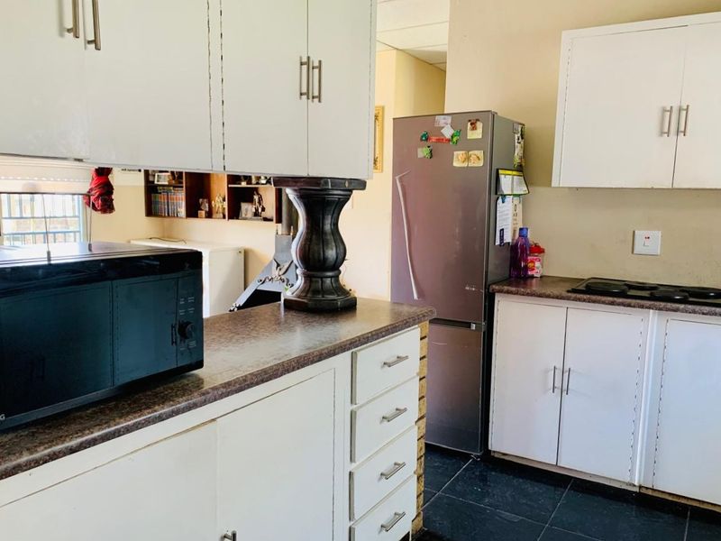 A functional kitchen featuring white built-in cabinetry, laminate countertops, and a built-in hob, offering a practical layout for daily meal preparation.
