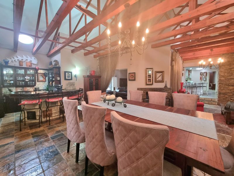 Spacious open-plan dining and bar area featuring high vaulted ceilings with exposed timber trusses, slate flooring, and a rustic stone-clad bar.