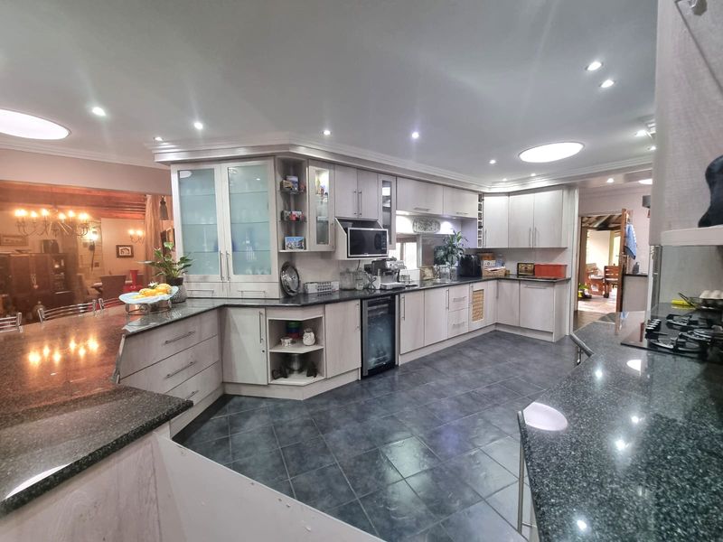 Spacious kitchen featuring extensive light-toned cabinetry, granite countertops, integrated appliances, and dark tiled flooring, offering a functional and well-lit culinary workspace.