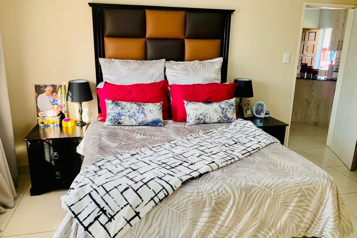 A well-maintained bedroom featuring neutral tiled flooring and a clear view into the adjacent living space.