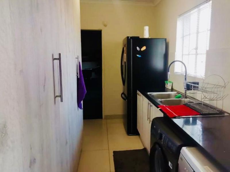 A functional kitchen area featuring built-in cabinetry, a double sink, and tiled flooring, providing a practical workspace for daily culinary needs.