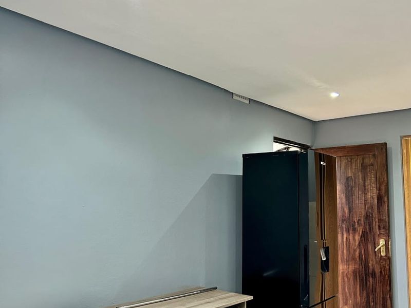 A bedroom featuring recessed downlighting and a solid timber door, providing a functional space with neutral wall tones.