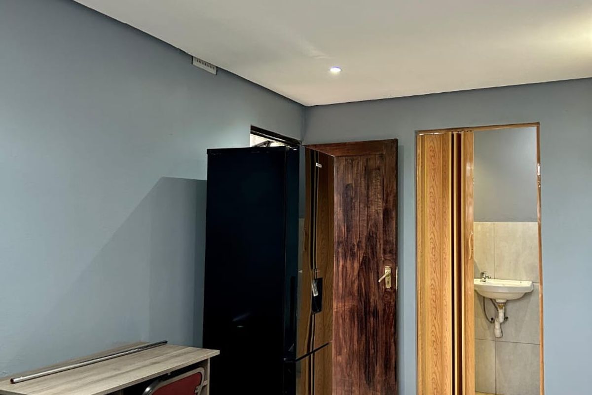 A bedroom featuring tiled flooring, recessed lighting, and an en-suite bathroom area accessed via a folding door.