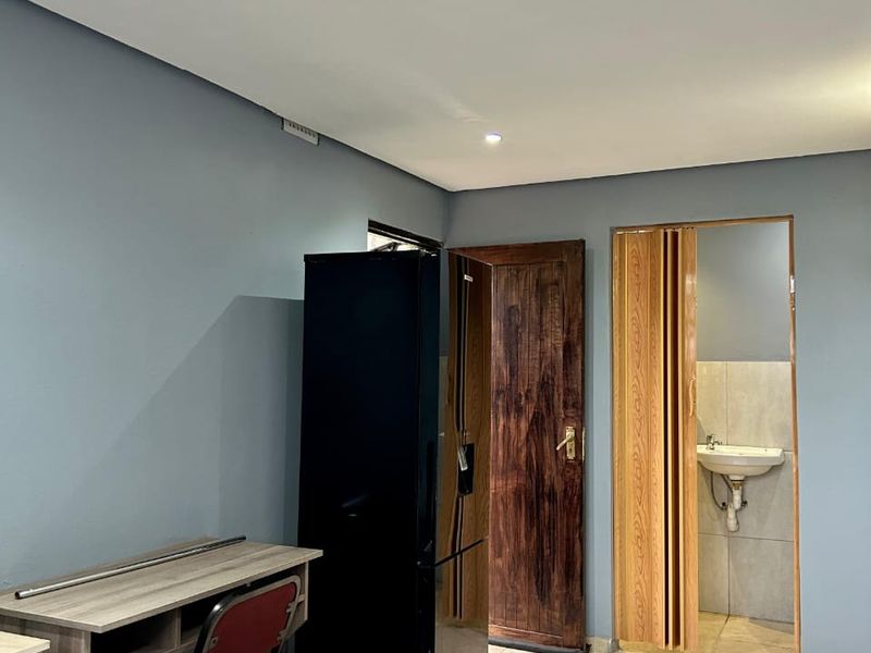 A bedroom featuring tiled flooring, recessed lighting, and an en-suite bathroom area accessed via a folding door.