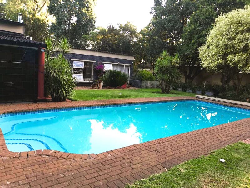 A well-maintained swimming pool area featuring brick paving and established garden landscaping, providing a pleasant outdoor space for recreation.