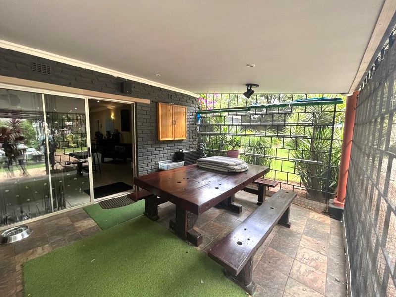 A covered patio area featuring tiled flooring, painted brick walls, and sliding glass doors providing access to the interior living space.