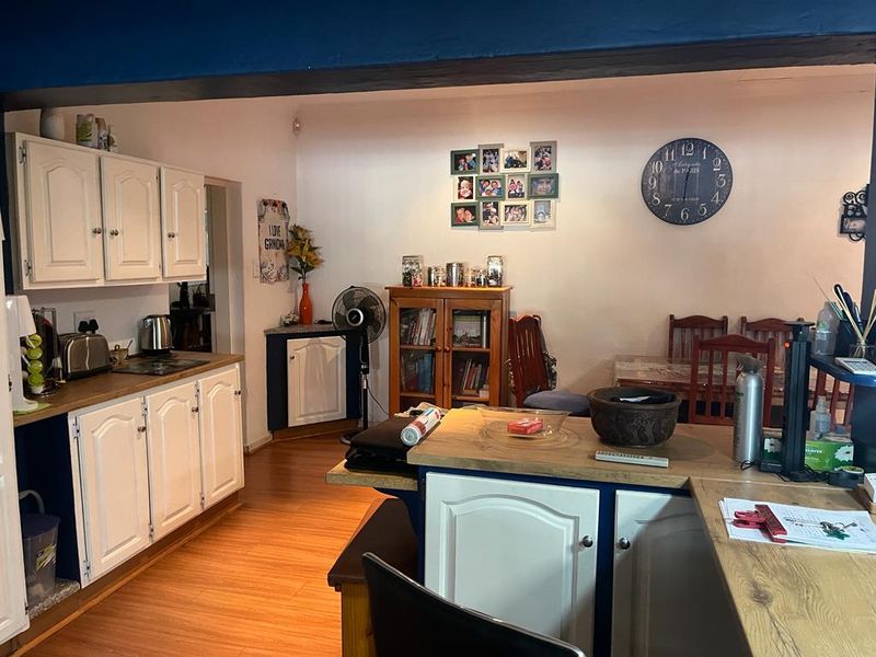 Open plan kitchen and dining area featuring white cabinetry, timber countertops, and laminate flooring, creating a functional and connected living space.