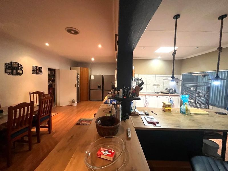 Open plan living and kitchen area featuring a central island, wooden flooring, and integrated cabinetry with a tiled backsplash.