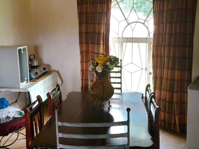 A dining room featuring tiled flooring and a decorative leaded glass window with curtains.