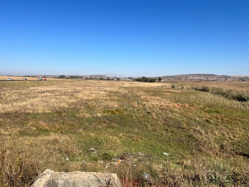 An expansive view of open farm land and natural landscape under a clear blue sky.