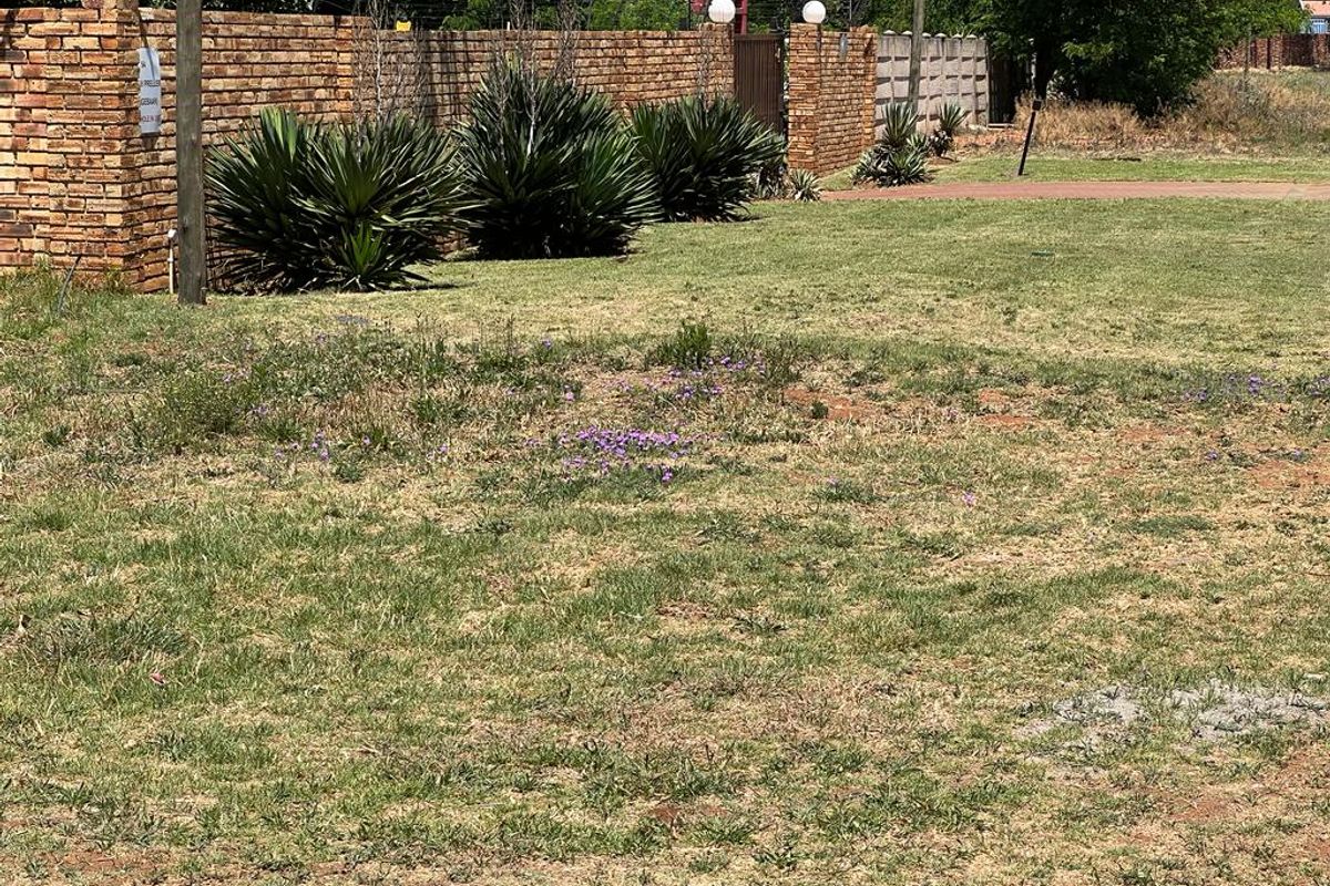 A view of a residential garden area featuring a brick boundary wall with integrated electric fencing and established shrubbery.