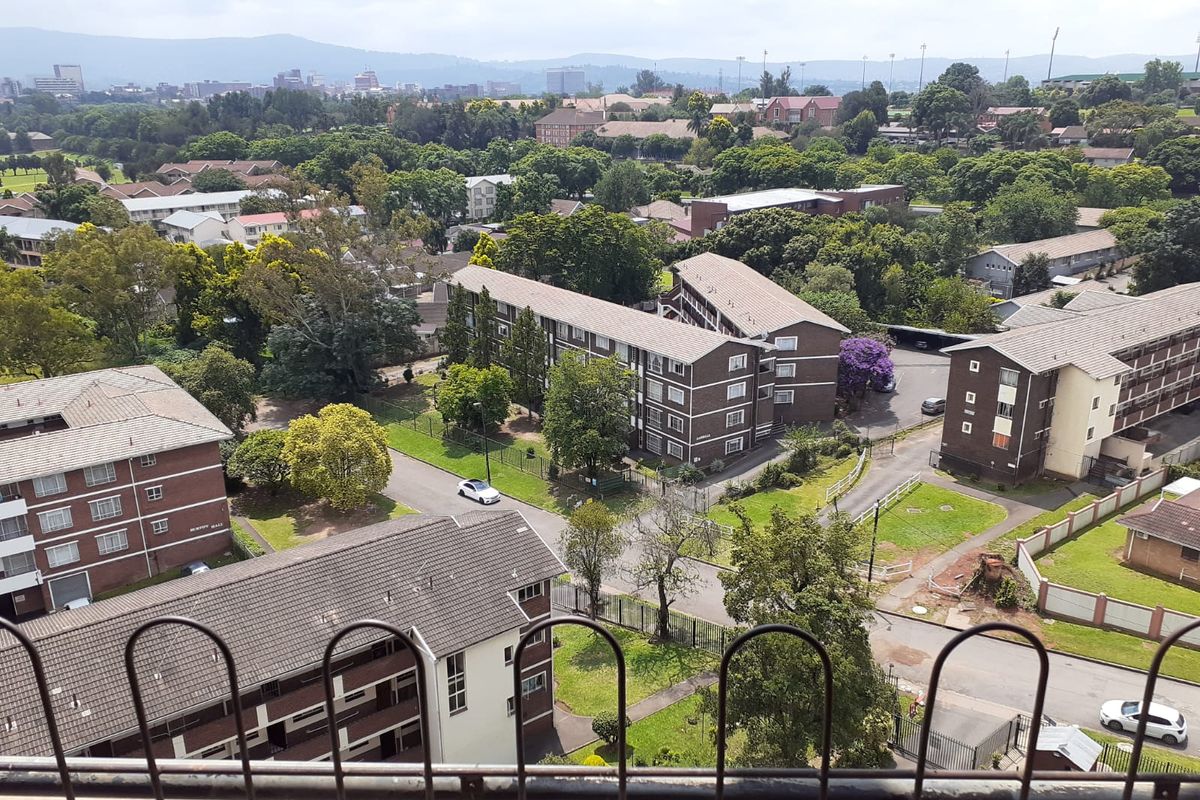 Elevated aerial view overlooking the surrounding residential apartment complex, landscaped grounds, and distant cityscape.