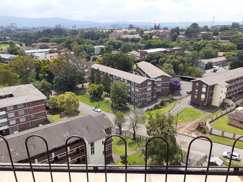 Elevated aerial view overlooking the surrounding residential apartment complex, landscaped grounds, and distant cityscape.