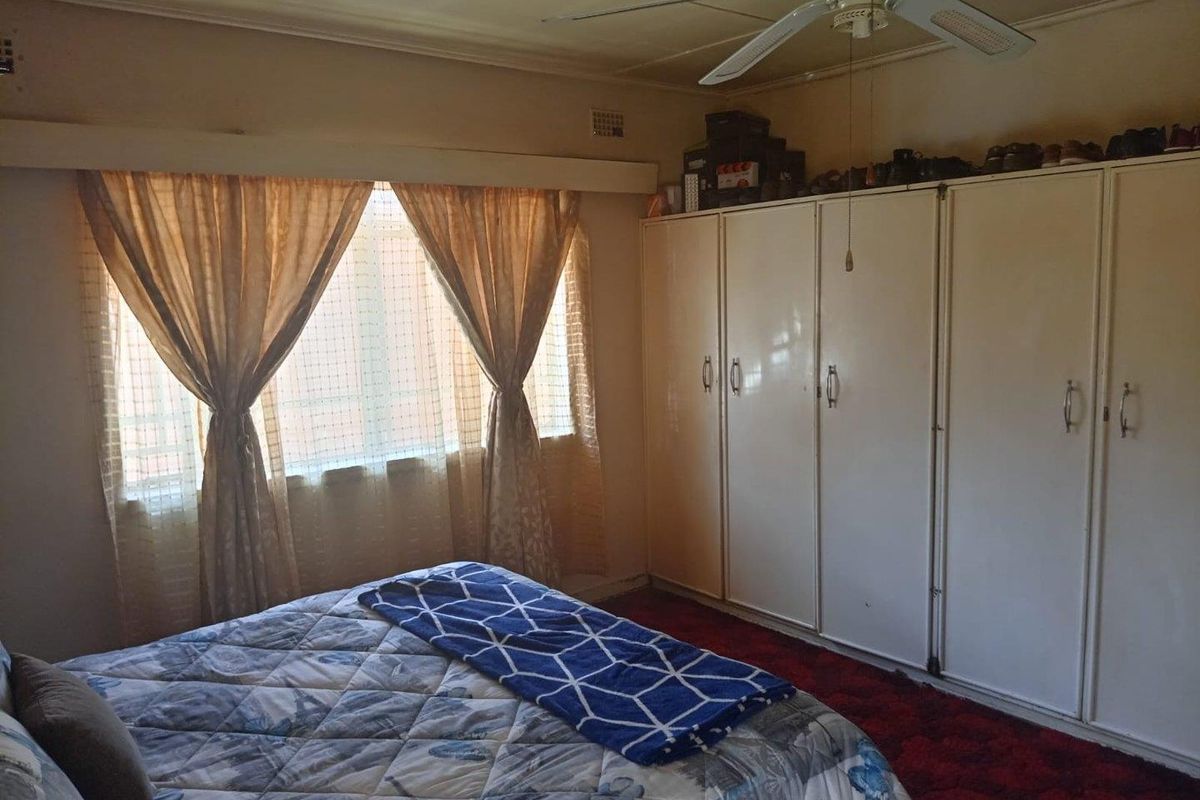 A bedroom featuring built-in cupboards and a ceiling fan, with carpeted flooring and natural light from the window.