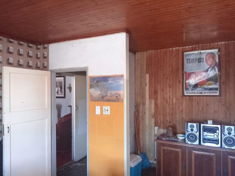 Living area featuring timber ceiling and wall paneling with a tiled accent wall, offering potential for modernization and aesthetic updates.