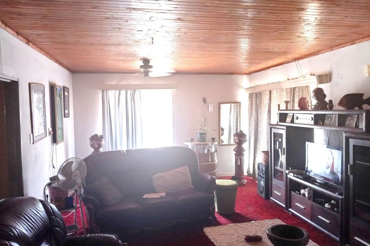A living room featuring a timber-clad ceiling and a ceiling fan, offering a dated aesthetic with potential for modernization.