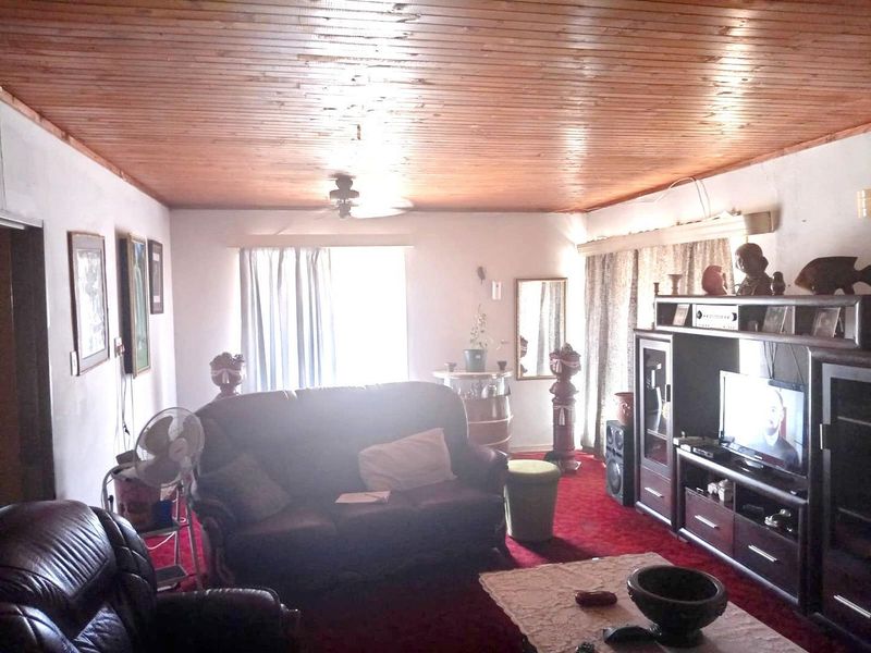 A living room featuring a timber-clad ceiling and a ceiling fan, offering a dated aesthetic with potential for modernization.
