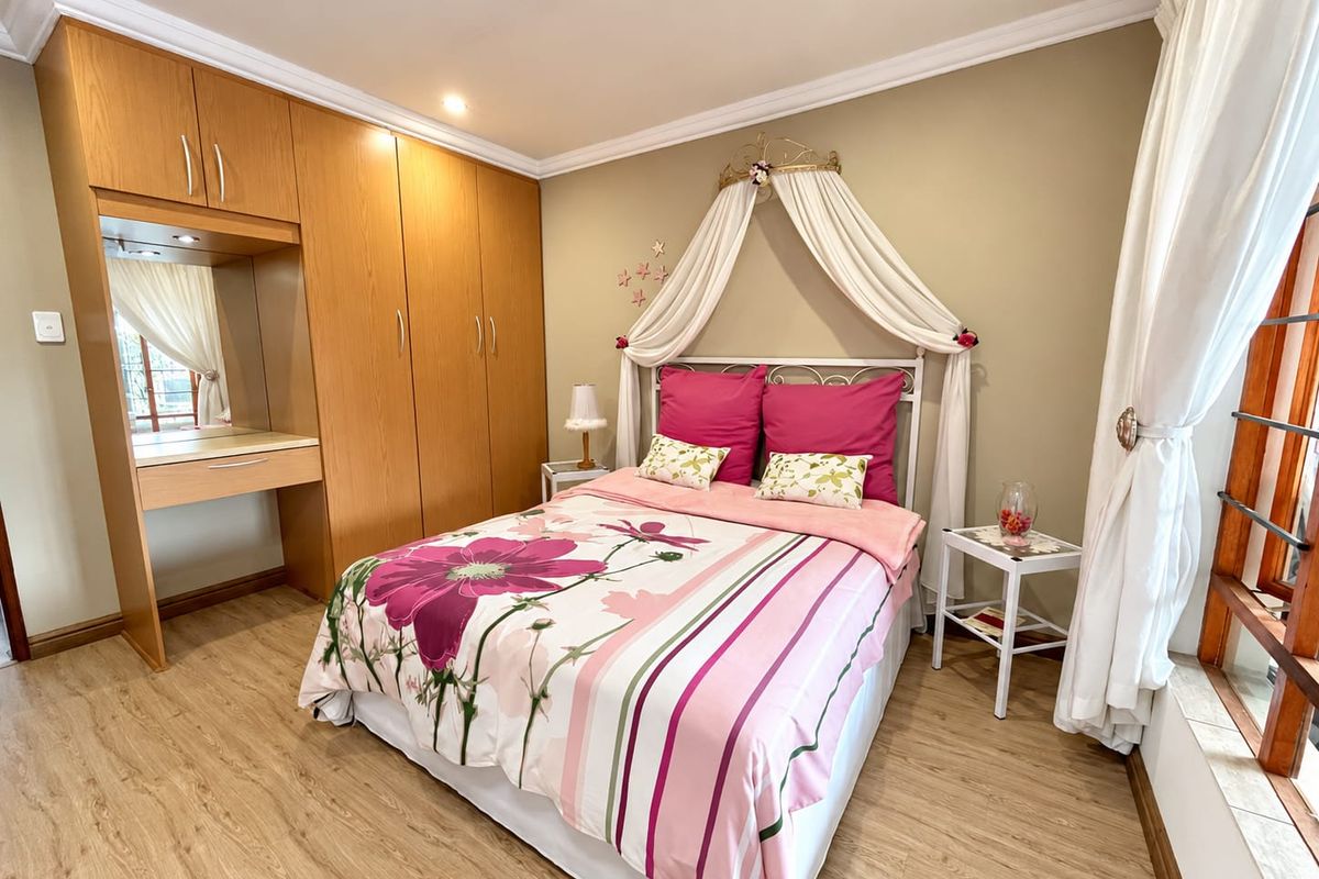 A well-maintained bedroom featuring light wood-look laminate flooring, built-in cabinetry with an integrated vanity, and recessed ceiling lighting.
