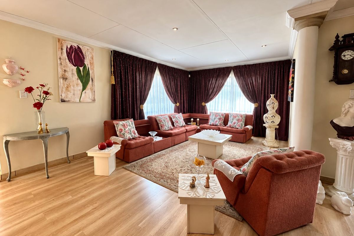 Spacious living room featuring light wood-look laminate flooring, recessed ceiling lighting, and a decorative column, creating a comfortable and inviting lounge area.