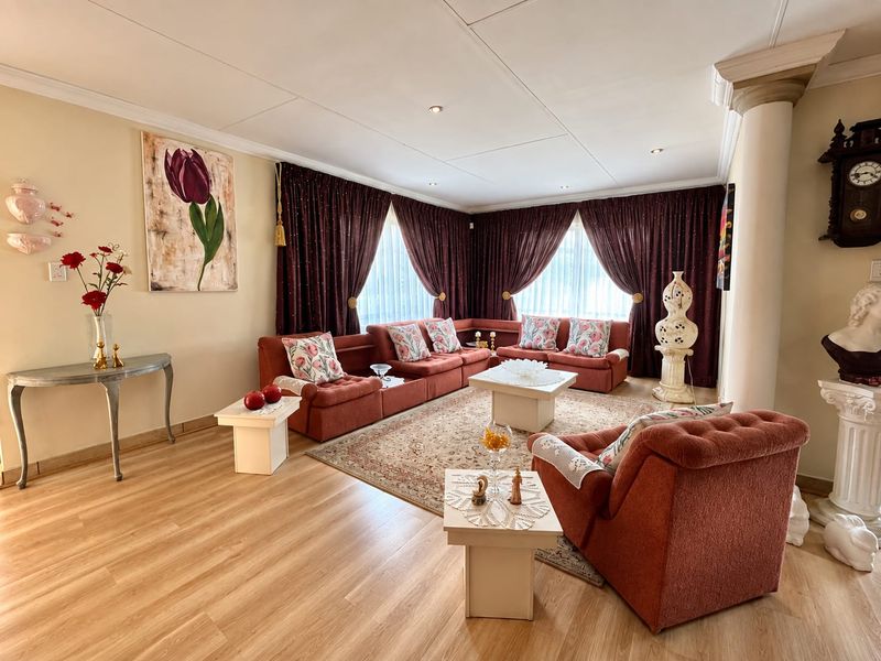 Spacious living room featuring light wood-look laminate flooring, recessed ceiling lighting, and a decorative column, creating a comfortable and inviting lounge area.