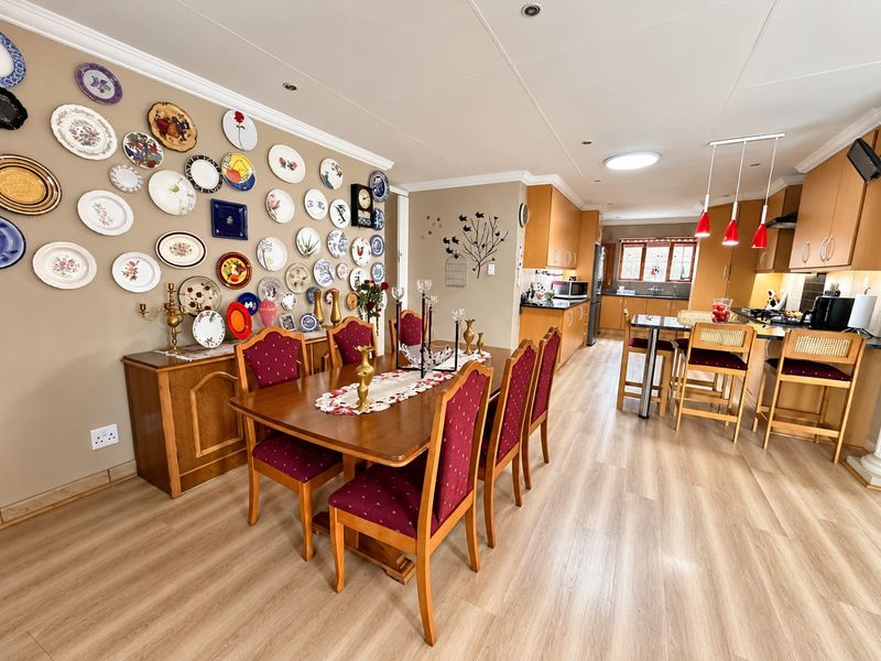 Spacious open-plan dining and kitchen area featuring modern laminate flooring, ample built-in cabinetry, and a functional breakfast bar island.