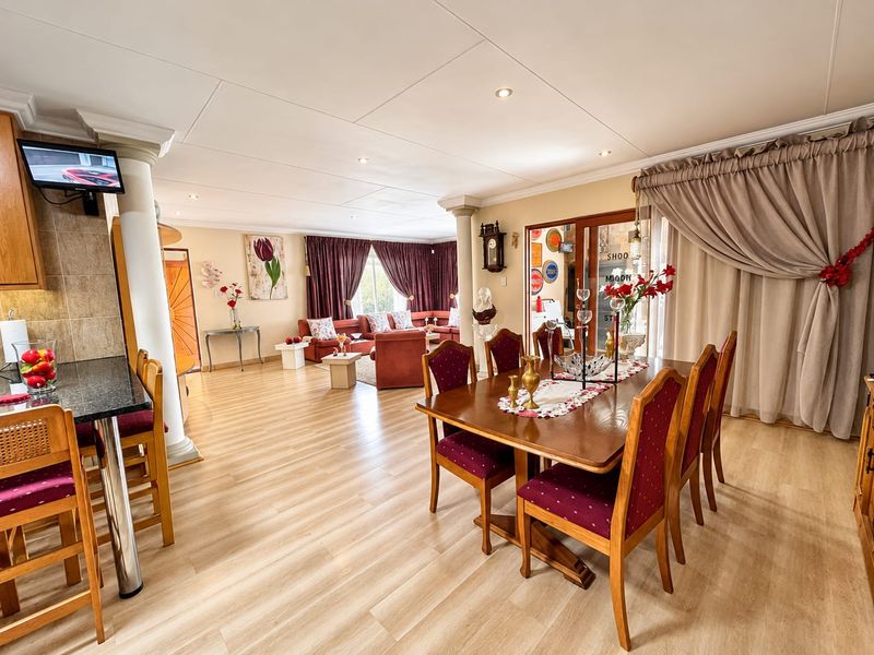 Spacious open-plan living and dining area featuring laminate flooring, recessed lighting, and seamless flow between the kitchen breakfast bar and lounge space.