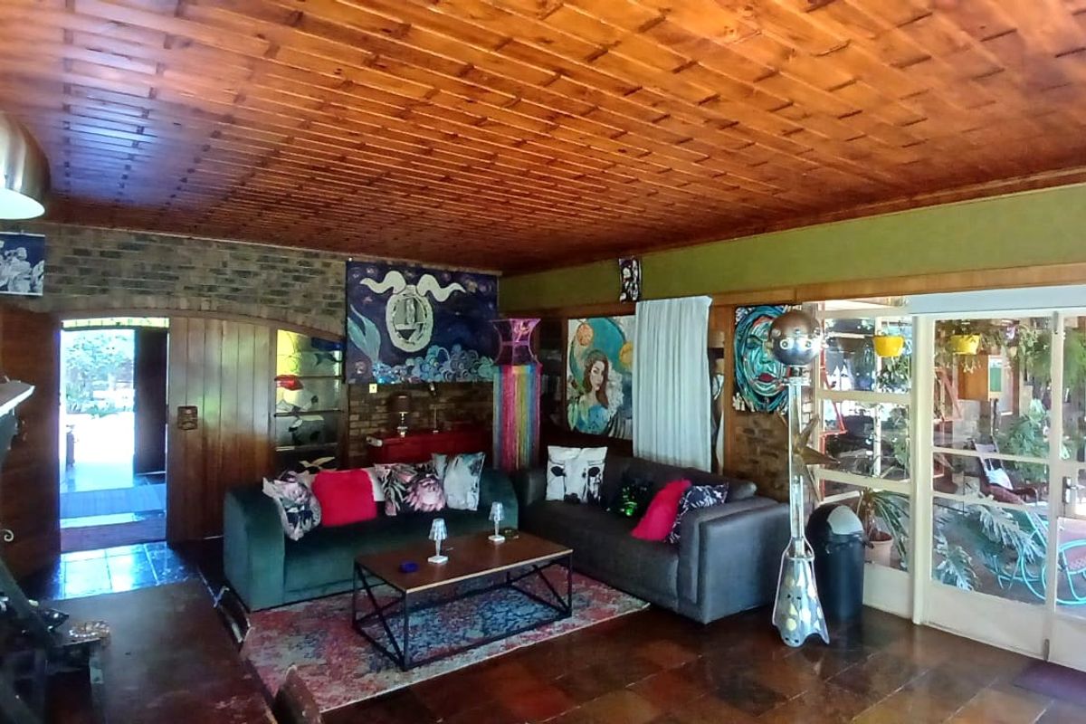 Spacious living room featuring a warm timber tongue and groove ceiling, exposed brick accents, and tiled flooring with direct access to an outdoor patio area.