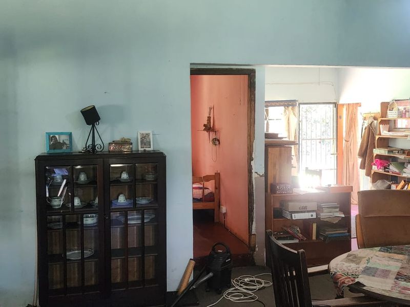 A living area showing signs of wear with visible wall damage and exposed wiring, offering potential for renovation and modernization.