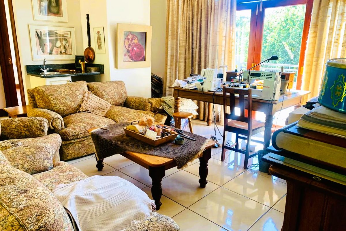 A living room featuring tiled flooring, a built-in bar area with a sink and granite countertop, and double glass doors leading to the exterior.