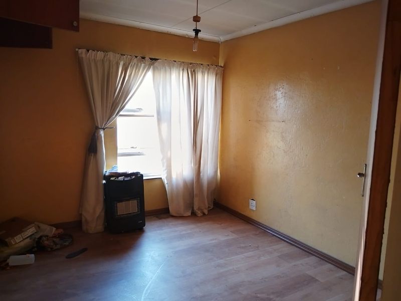 A vacant bedroom featuring laminate flooring and neutral wall finishes, offering a blank canvas for potential renovation and interior design updates.