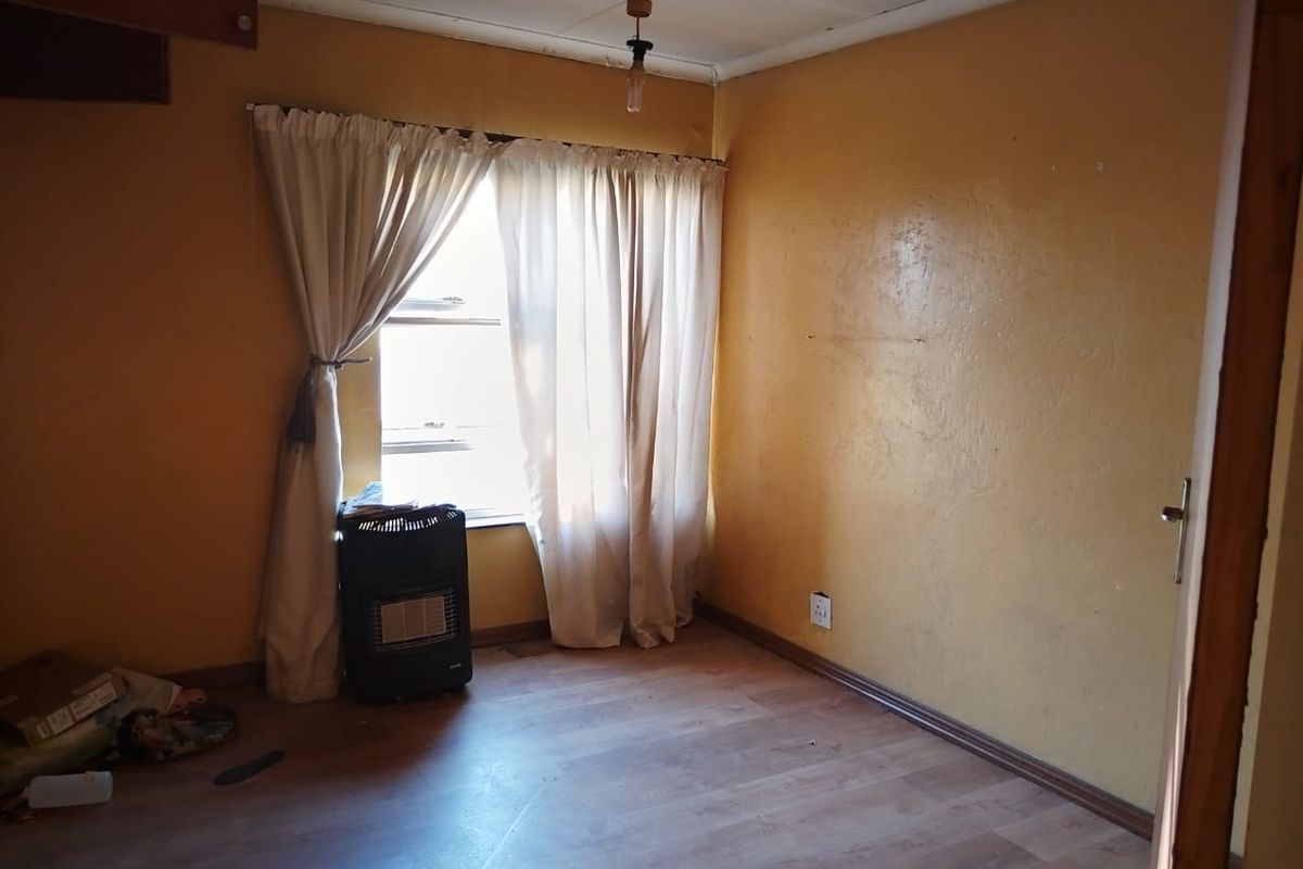 A vacant bedroom featuring laminate flooring and neutral wall finishes, offering a blank canvas for potential renovation and interior design updates.