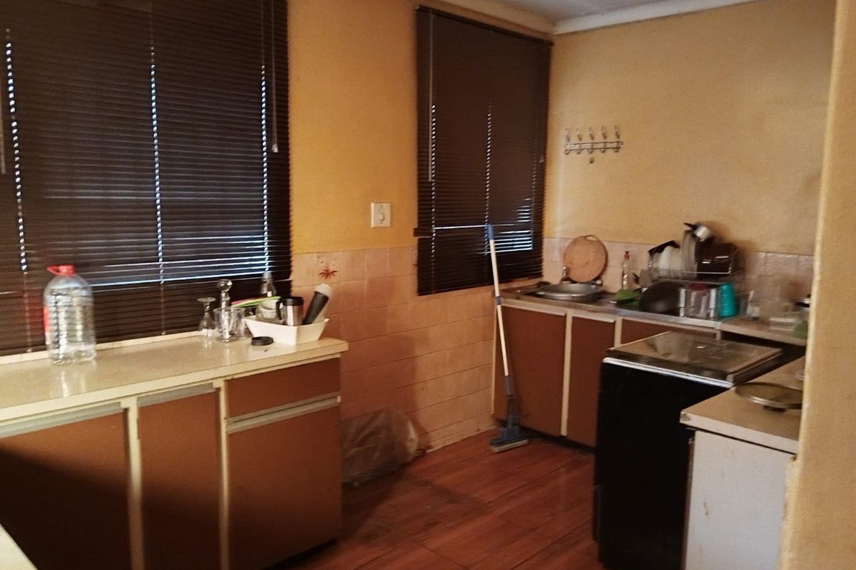 A dated kitchen featuring built-in cabinetry, laminate countertops, and a tiled backsplash, offering significant potential for modernization and renovation.