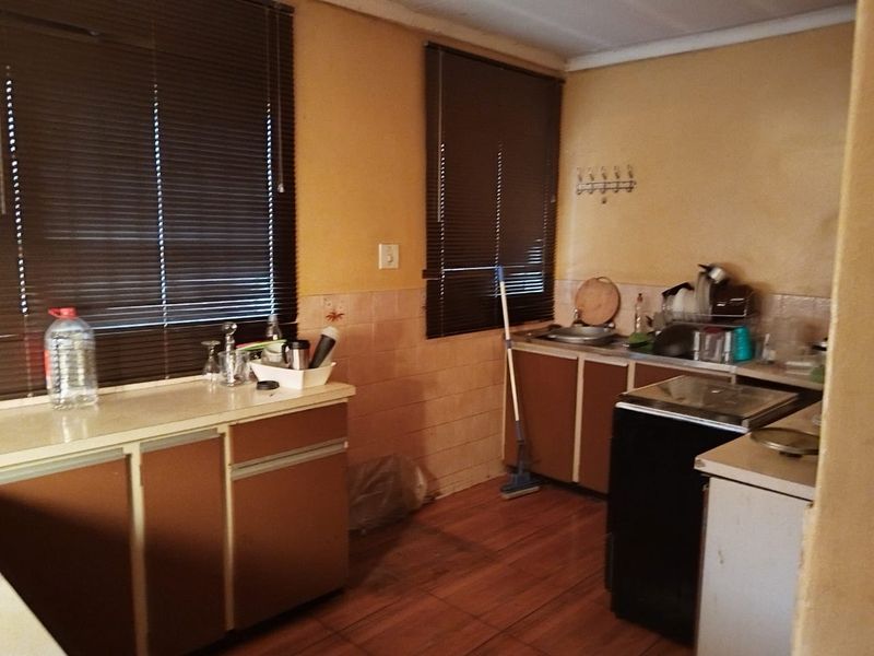 A dated kitchen featuring built-in cabinetry, laminate countertops, and a tiled backsplash, offering significant potential for modernization and renovation.