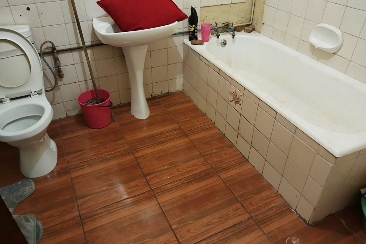 A dated bathroom featuring a pedestal basin, bathtub, and tiled finishes, currently requiring renovation and modernization of fixtures and surfaces.