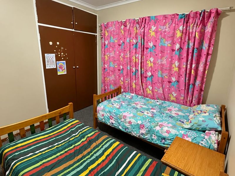 A functional bedroom featuring built-in cupboards and carpeted flooring, providing a practical space for rest.