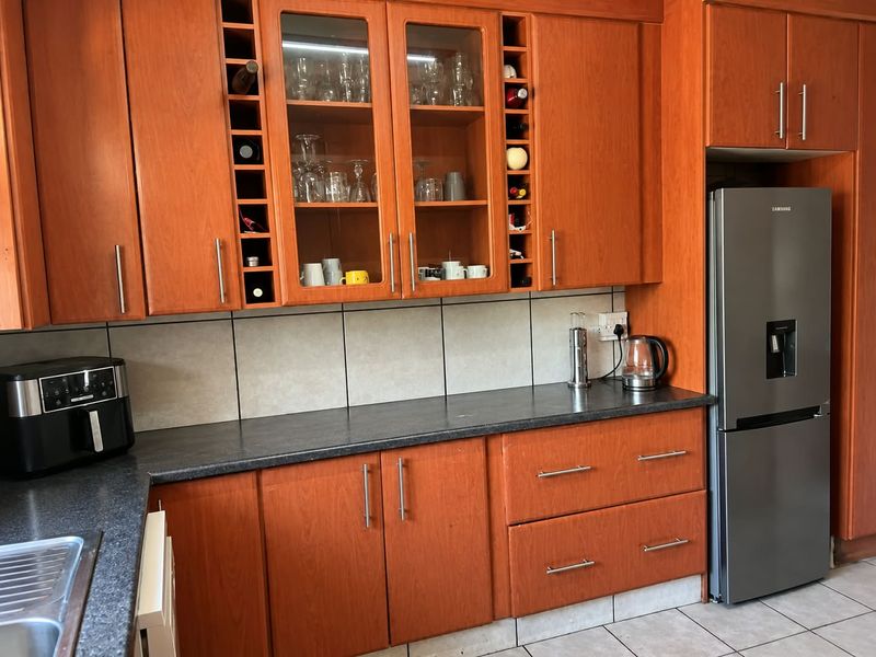 A functional kitchen featuring warm-toned wooden cabinetry, dark laminate countertops, a tiled backsplash, and dedicated built-in wine storage.