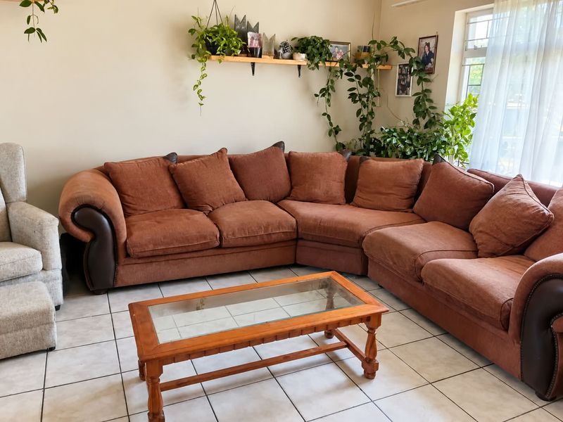 A living room area featuring neutral ceramic floor tiles and a window with security bars, providing a functional and well-lit space.