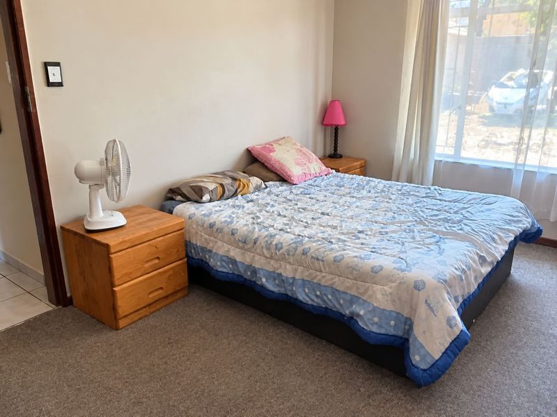 A functional bedroom featuring carpeted flooring and a large window that allows for natural light.