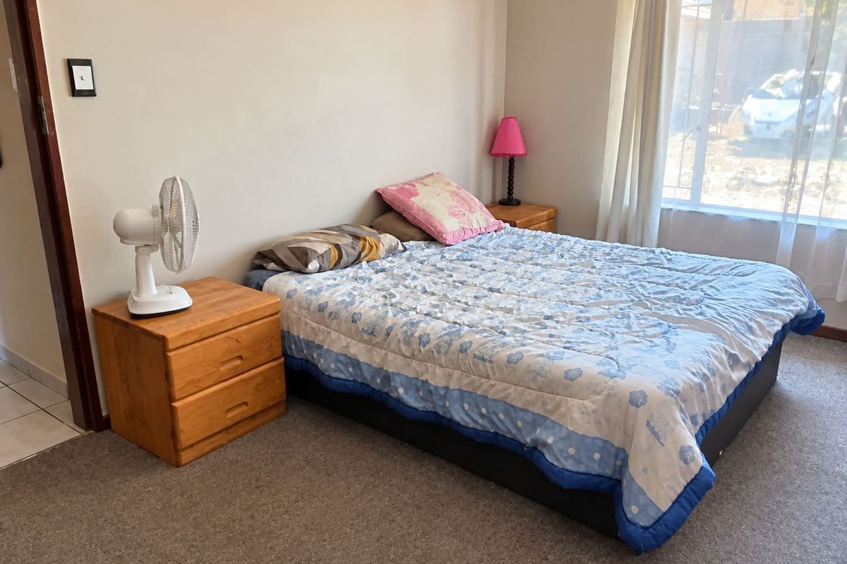 A functional bedroom featuring carpeted flooring and a large window that allows for natural light.
