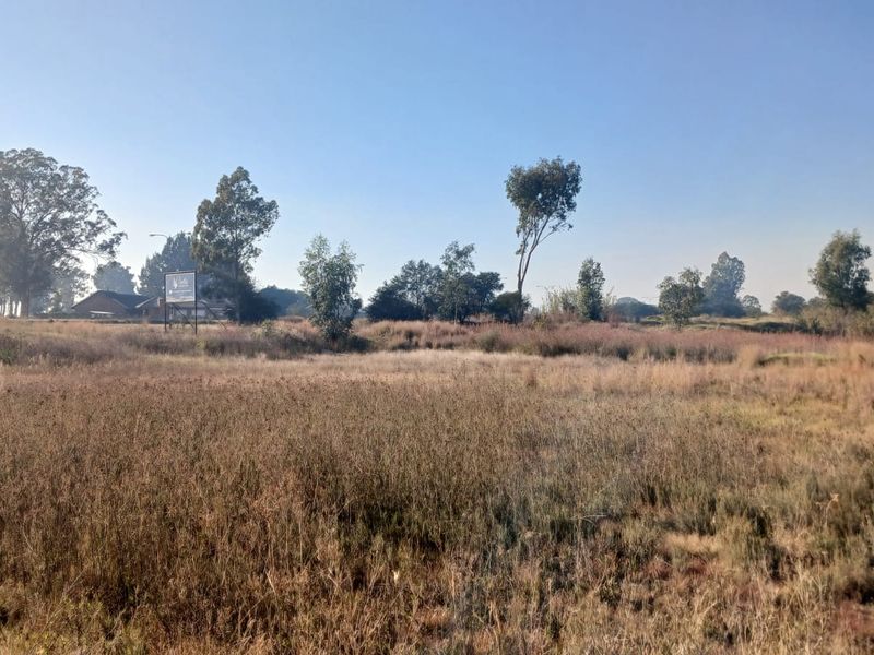 A view of a vacant residential plot featuring natural vegetation and mature trees, suitable for future development.
