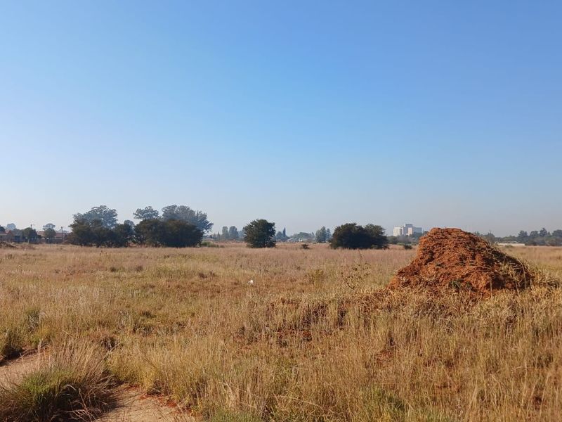 A wide-angle view of a vacant residential plot featuring natural grass and open landscape.