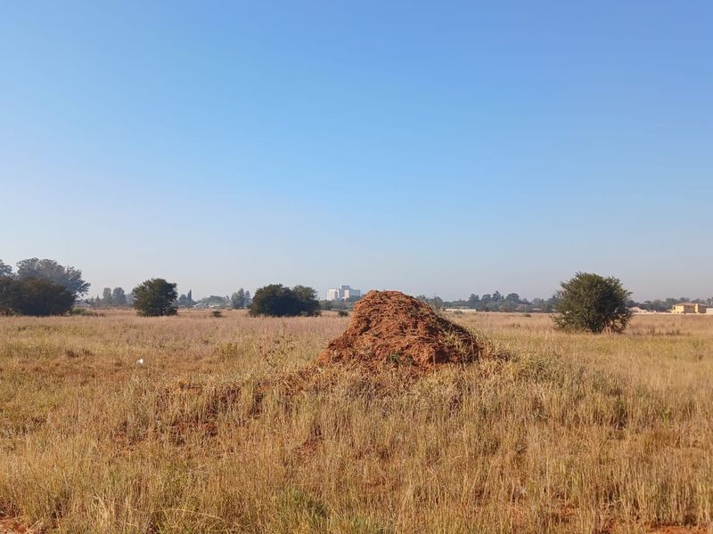 A wide-angle view of a vacant residential plot featuring natural grass cover and open terrain, suitable for future development.