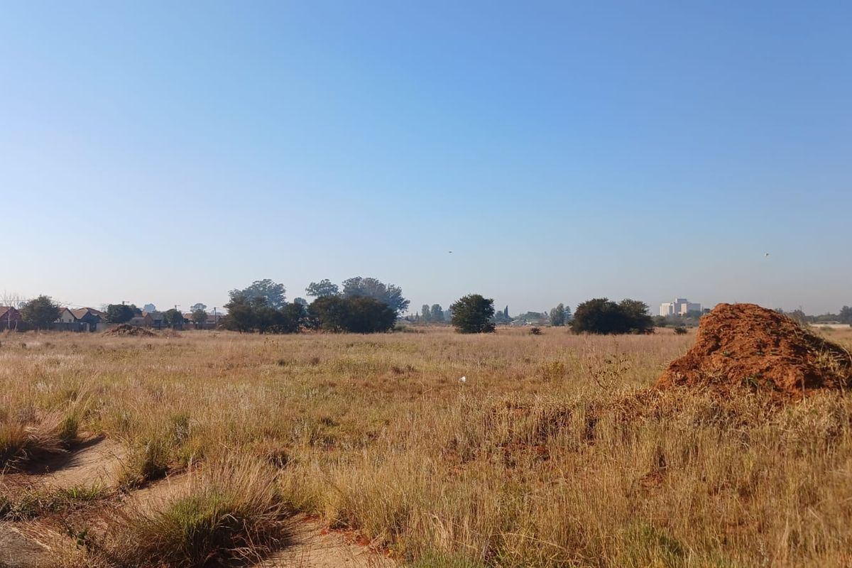 A wide-angle view of a vacant residential plot featuring natural grassland and open space, suitable for future development.