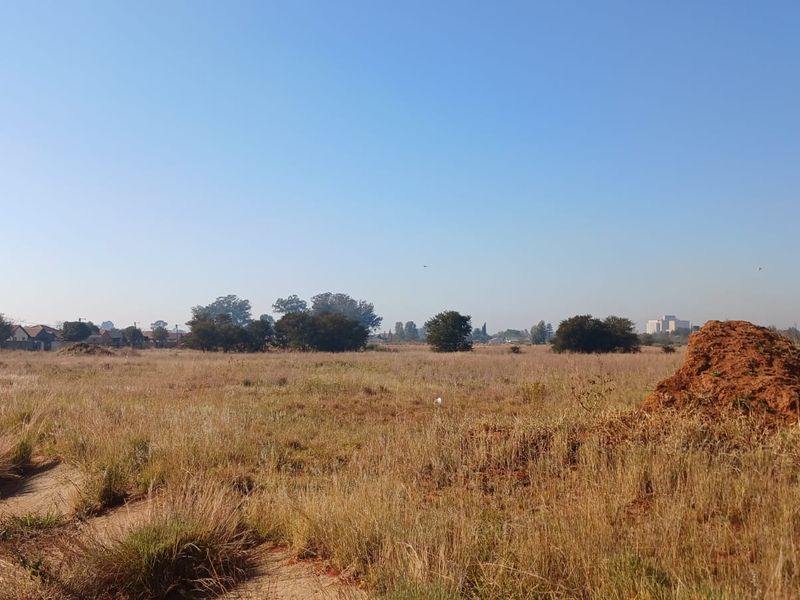 A wide-angle view of a vacant residential plot featuring natural grassland and open space, suitable for future development.