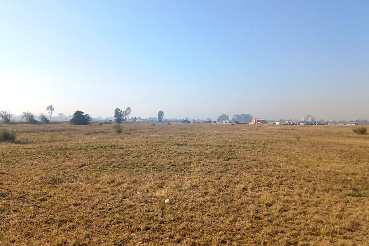 A wide, open expanse of vacant residential land featuring natural grass cover and distant horizon views.